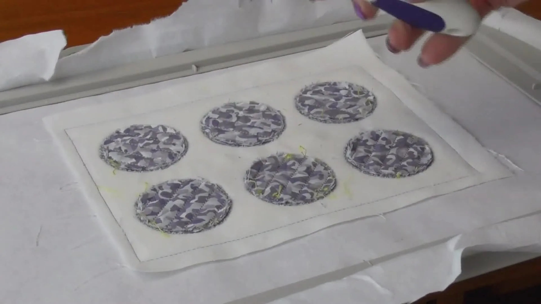 A close overhead view of slashing chenille channels with a purple cutter while the project stays hooped for tension and control.
