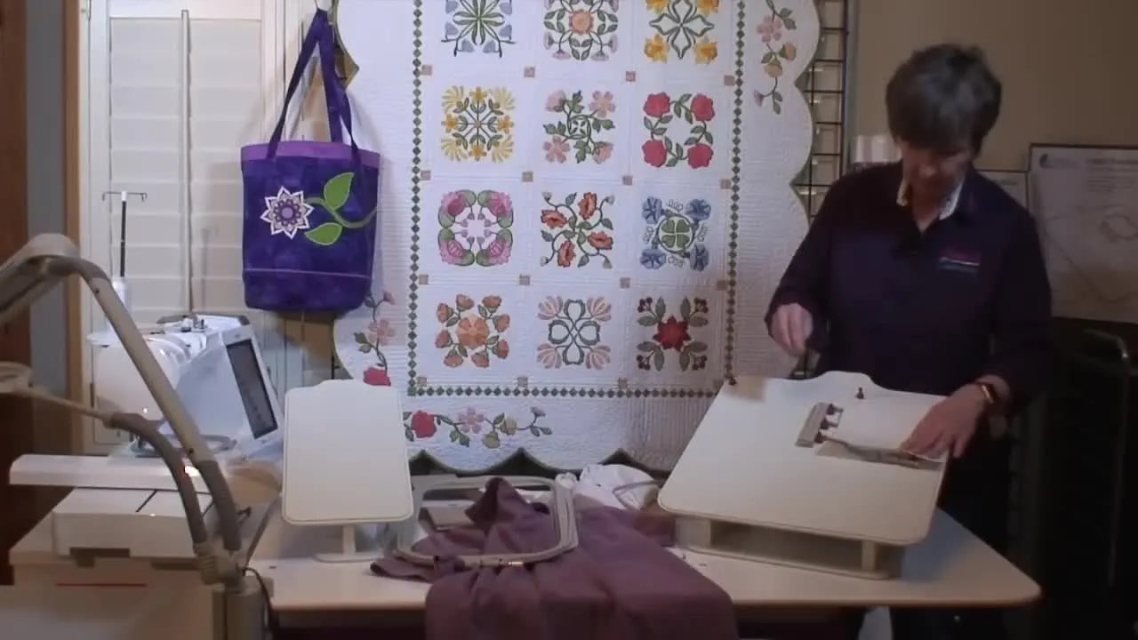 A purple t-shirt is slid smoothly over the large side of the hooping station, showing how the garment stays controlled and flat before the inner hoop is pressed in.