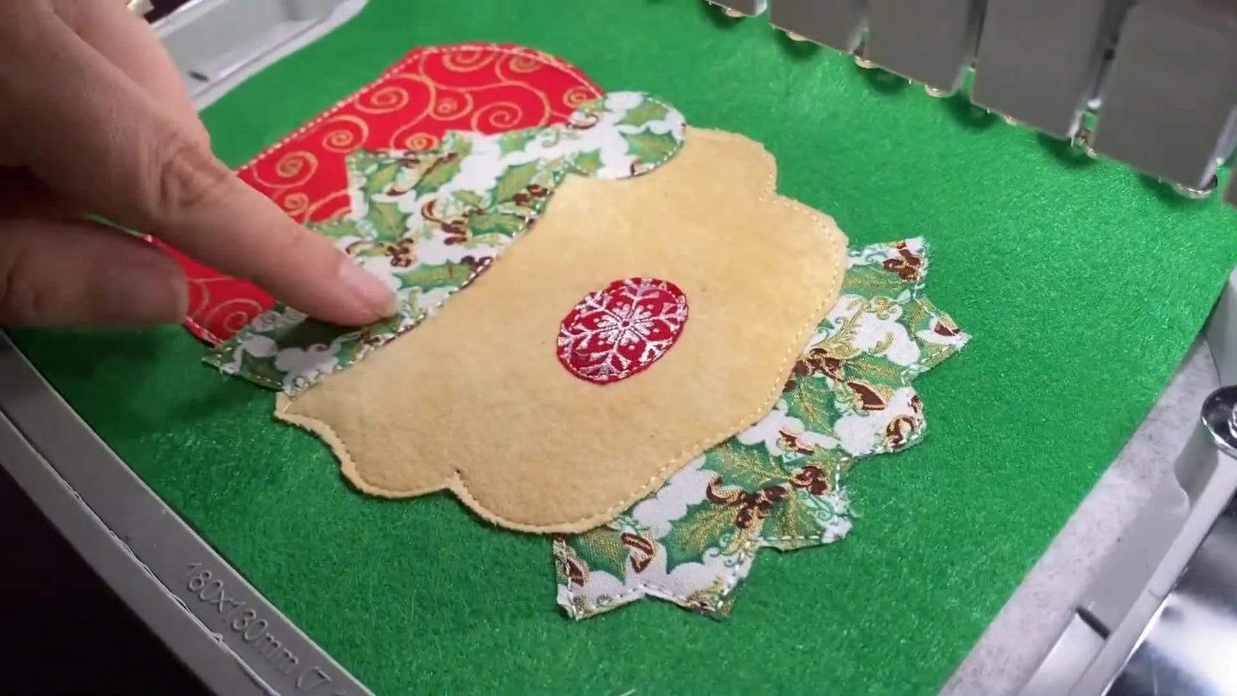 A top-down view of the completed elf face appliqué in the hoop, showing clean satin stitches and crisp fabric edges before bag construction.