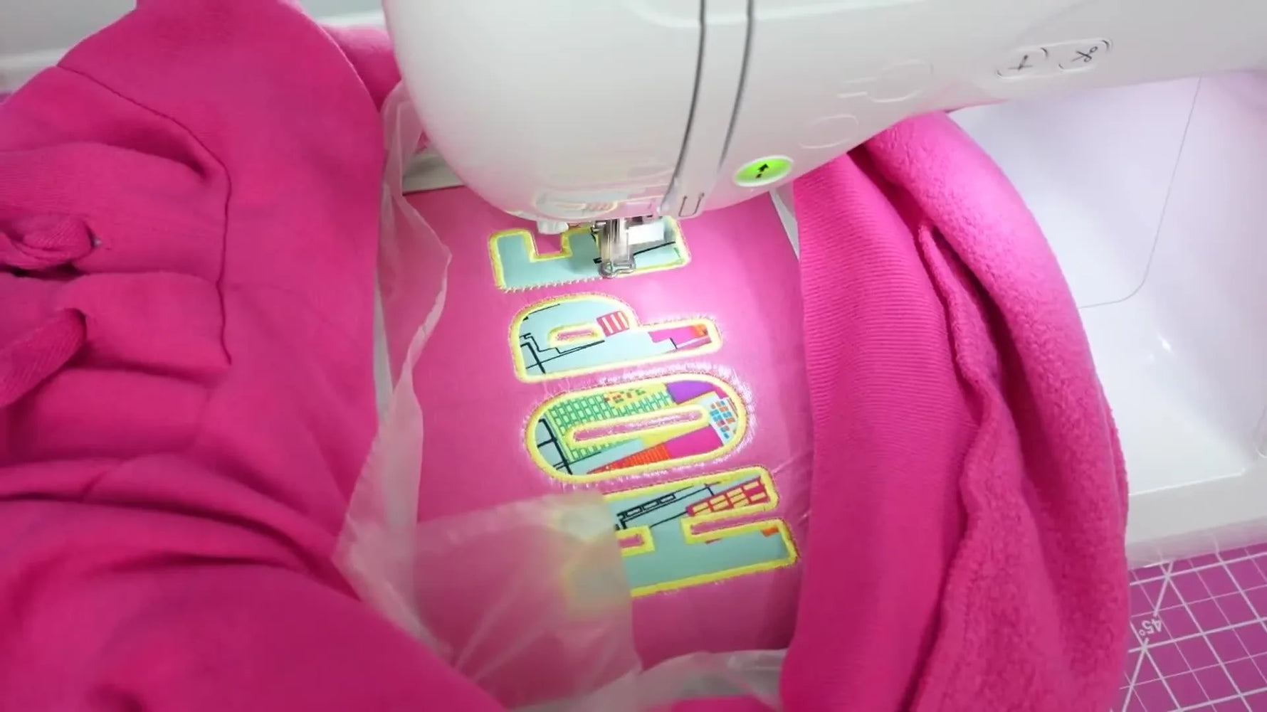 A close-up of the finished “HOPE” appliqué embroidery stitched on a pink hoodie while still hooped in the Brother PE800.