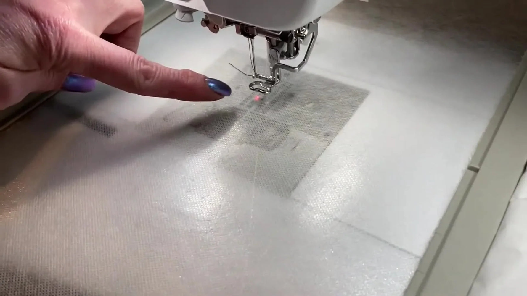 A close-up shows the Baby Lock Destiny II laser dot centered on the hooped stabilizer, ready for precise name placement on a pillowcase cuff.