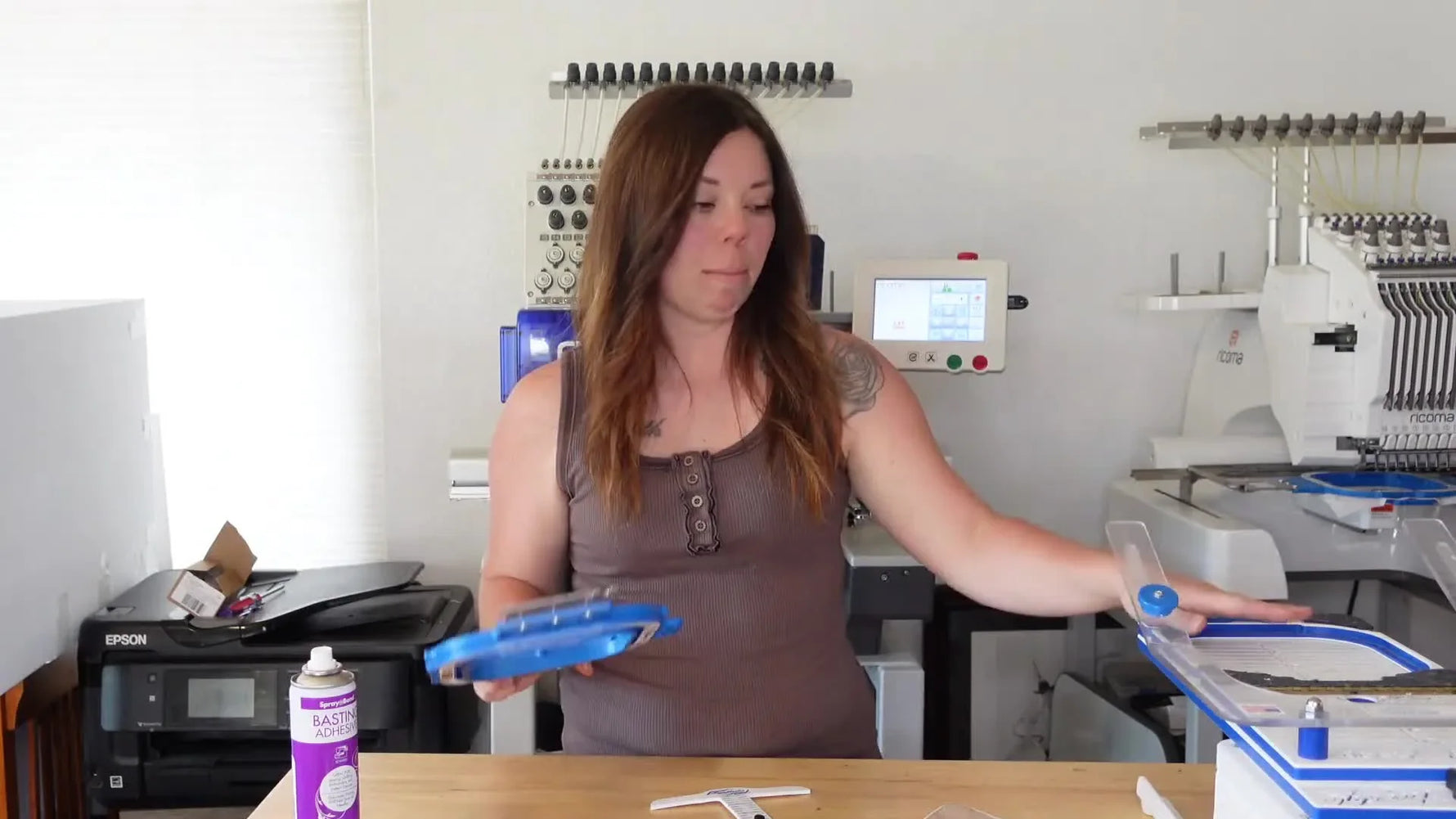 Woman holding up a 5x5 Mighty Hoop and a pocket square, showcasing embroidery essentials.