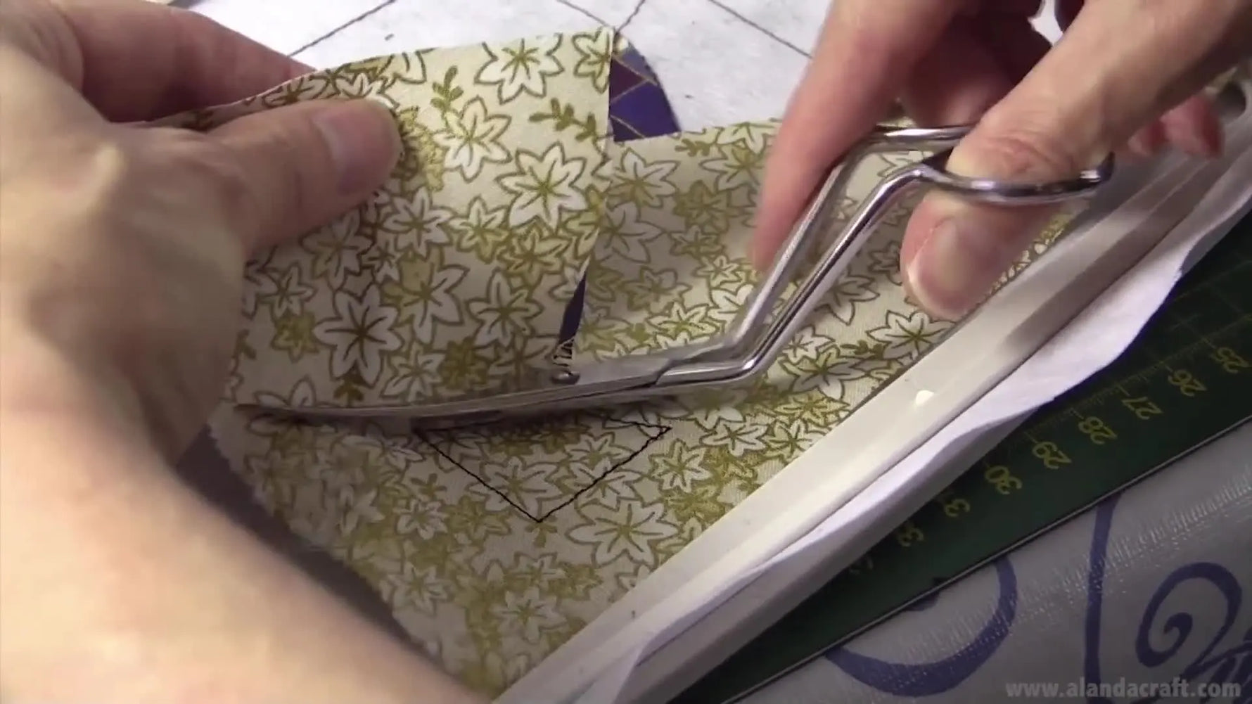 A close-up shows applique scissors making a curved overlap cut right beside the stitch line to prevent gaps before the final satin stitch.