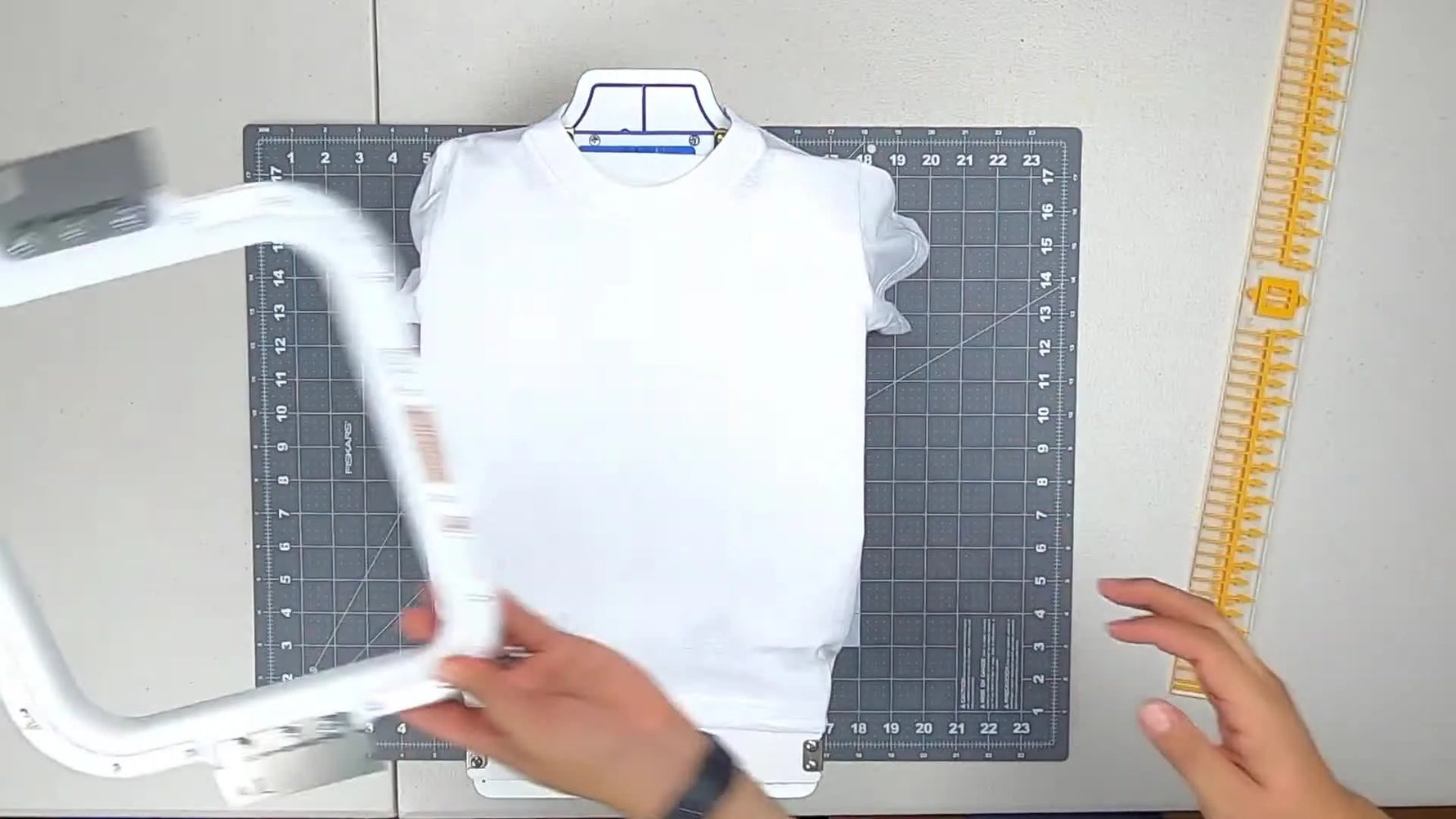 Overhead close-up of the top magnetic frame snapping down on a toddler t-shirt for fast, centered hooping.