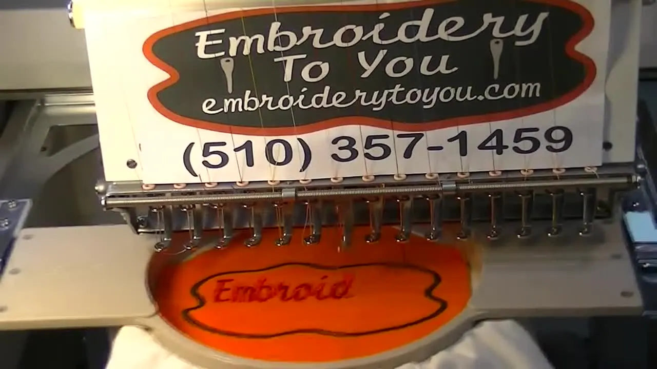 A finished appliqué logo sits cleanly inside an 18 cm tubular hoop on a tote bag, moments before the excess flock is torn away.