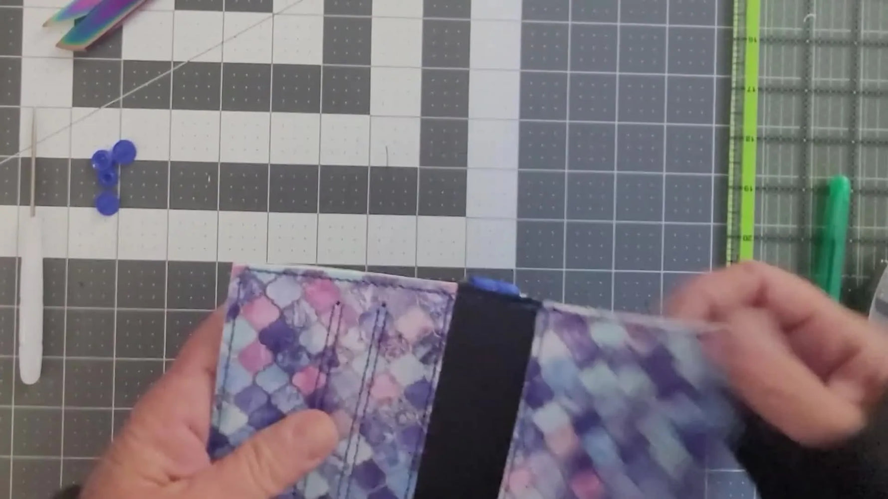 A finished minimalist vinyl wallet folded shut with a snap installed and a lobster-clasp tab attached.