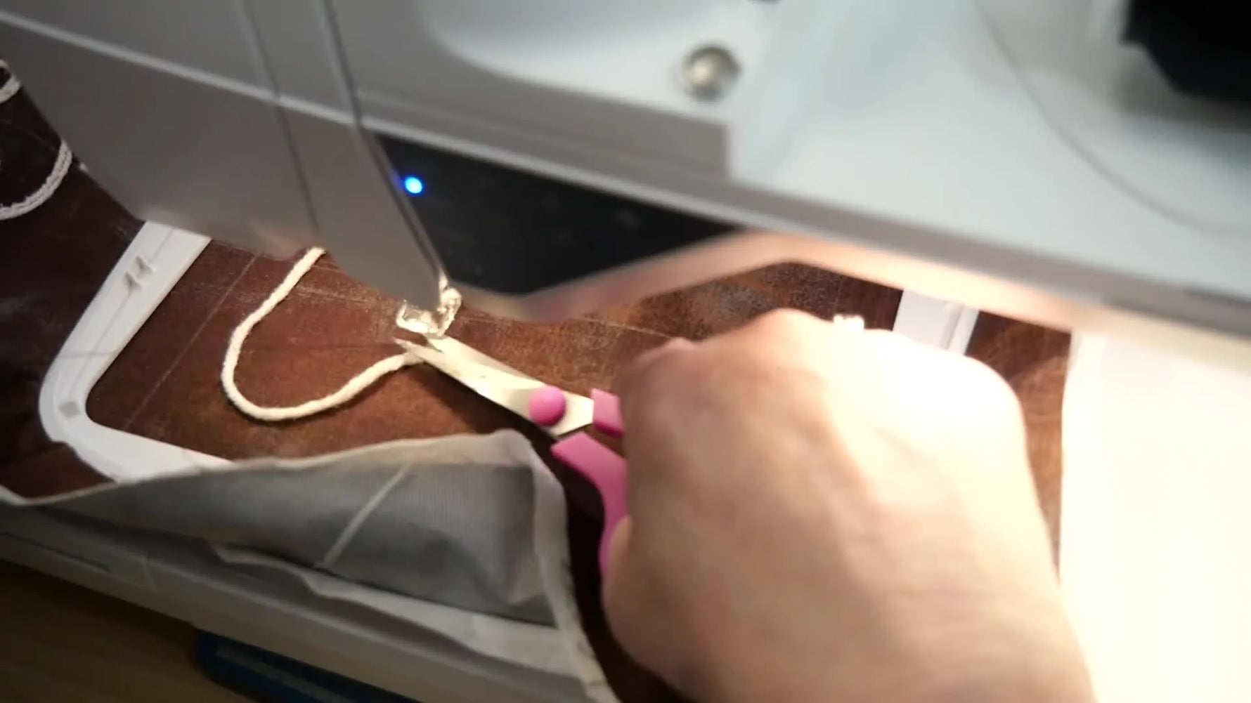 A close-up of the couching foot stitching a looping pattern while the yarn feeds smoothly under the needle.