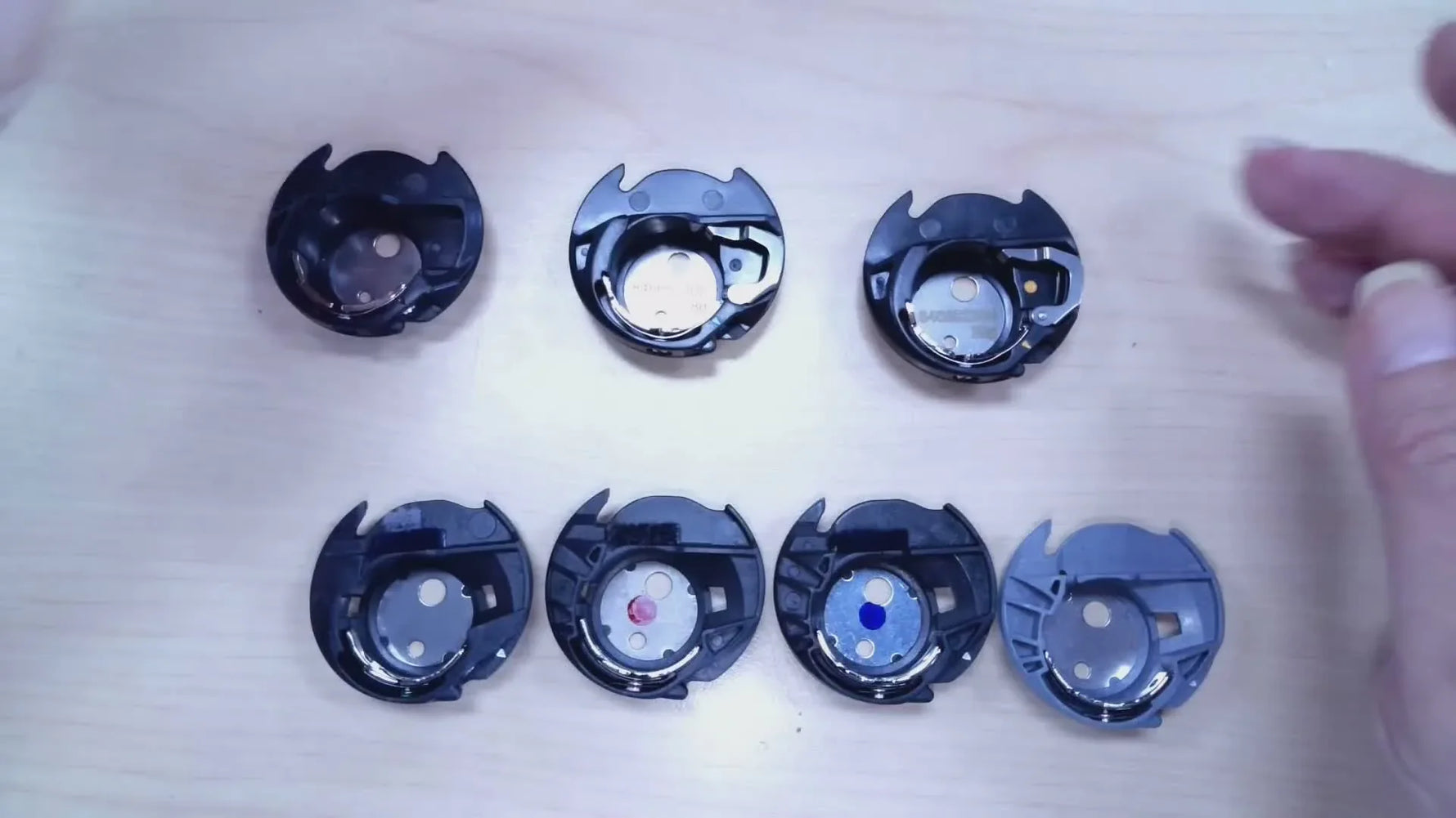 Four Janome bobbin cases are laid out side-by-side so you can compare their arrows, dots, and sensor-arm features at a glance.