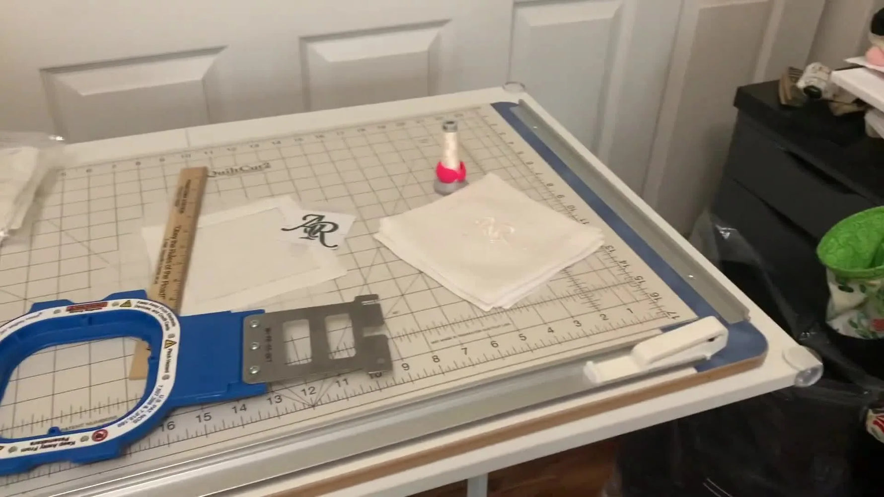 A magnetic hoop snaps down on a linen cocktail napkin at a hooping station, showing a fast, repeatable setup for production-style monogramming.