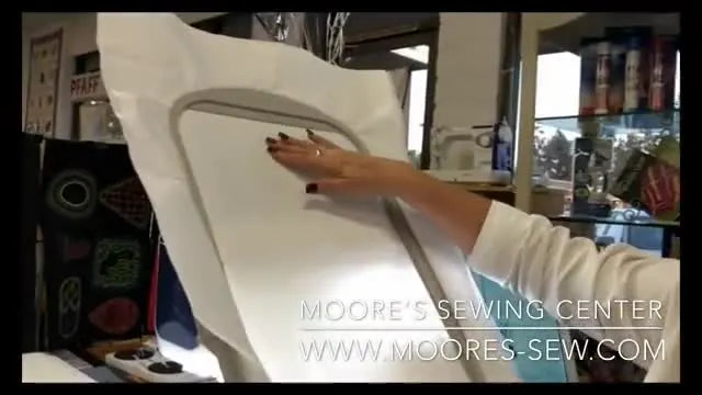 A staff member holds the oversized 10 5/8" x 16" Brother Luminaire hoop upright to show its scale and quick-release mechanism.