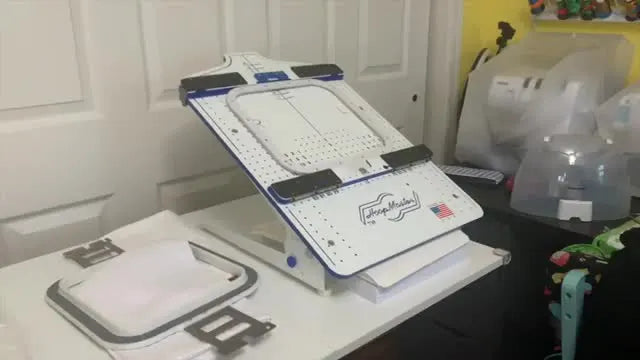 A hooping station is set up with tearaway stabilizer, ready for a waffle-weave towel to be aligned and clamped in a magnetic hoop.