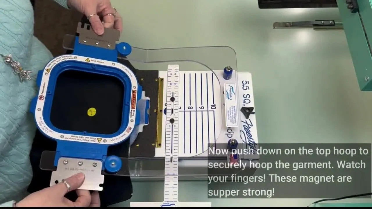 A magnetic Mighty Hoop snaps down on a garment in the HoopMaster setup, showing the fast clamp action that makes repeatable hooping possible.