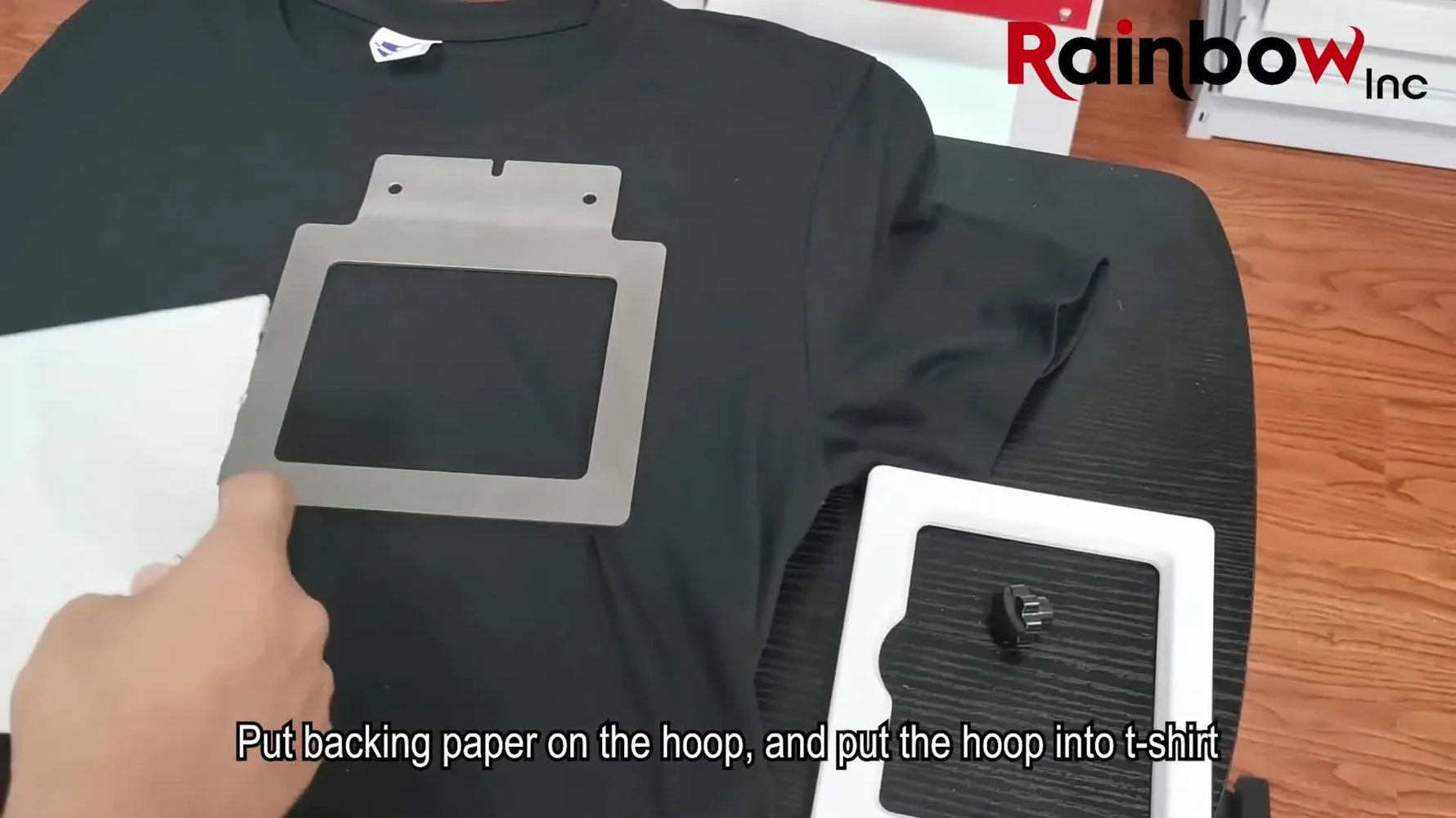 Hands snap a magnetic garment hoop onto a black T-shirt, showing the fast, even clamping that makes magnetic frames so popular in production.