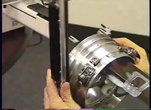 A technician demonstrates the correct, safe grip on the cap driver by holding the main ring to prevent bending the linkage.