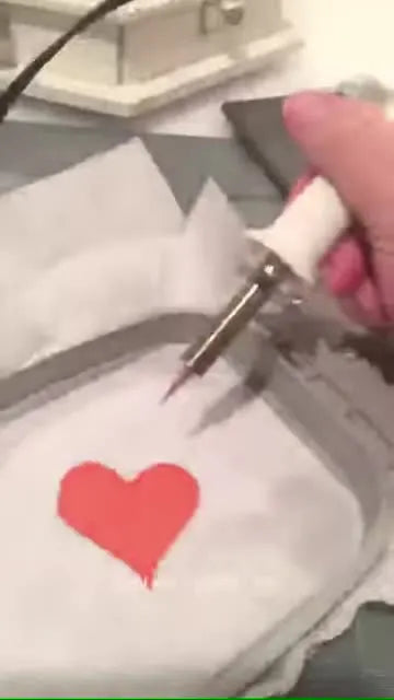 A heated Fuse Tool traces the outside of a satin-stitched heart while the Oly-Fun remains hooped tight for a clean, melted edge.