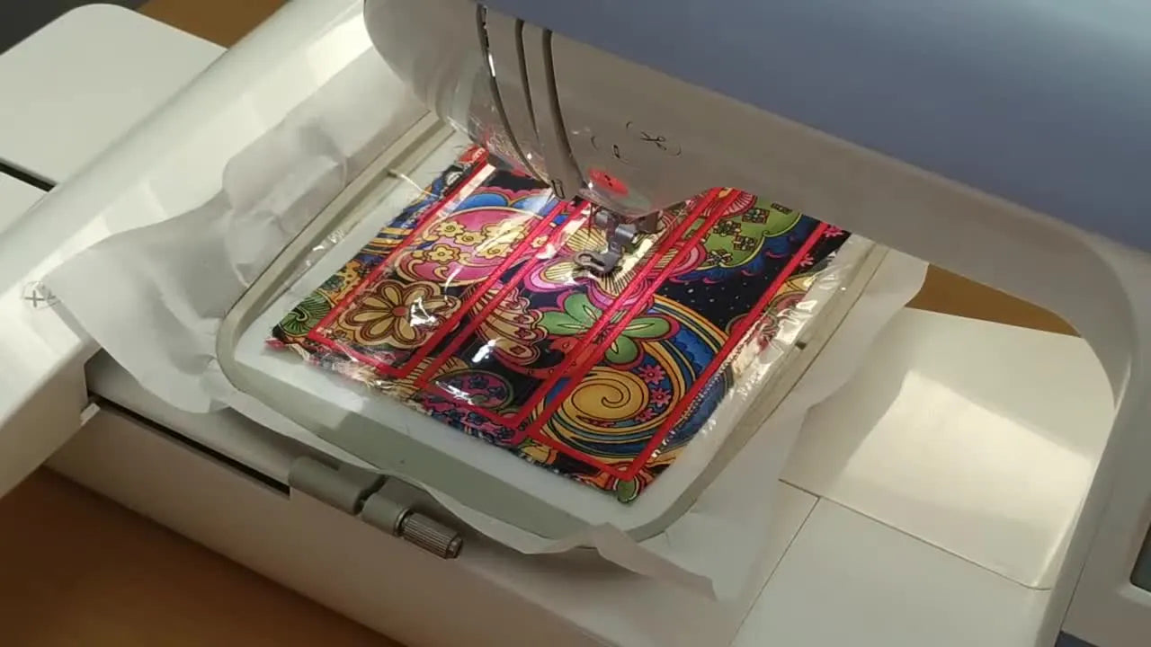 An overhead view of a 5x7 hoop holding three finished in-the-hoop bookmarks, including two with clear PVC pockets stitched in place.