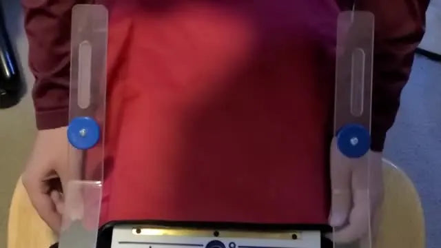Hands press a top magnetic hoop ring onto a red drawstring bag on a hooping station, locking the fabric and stabilizer in place for accurate embroidery.
