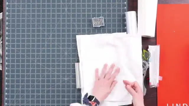 A thick terry cloth towel is carefully floated onto hooped sticky stabilizer, centered and ready for a crisp monogram stitch-out.