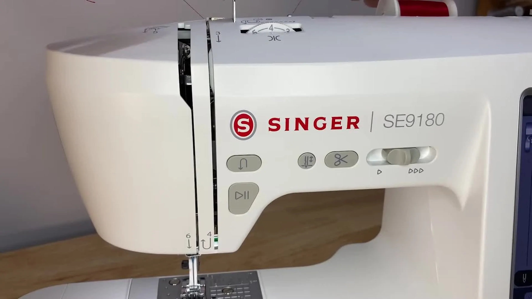 A close view of the SINGER SE9180 front channel as the upper thread is pulled downward in the correct tension path.