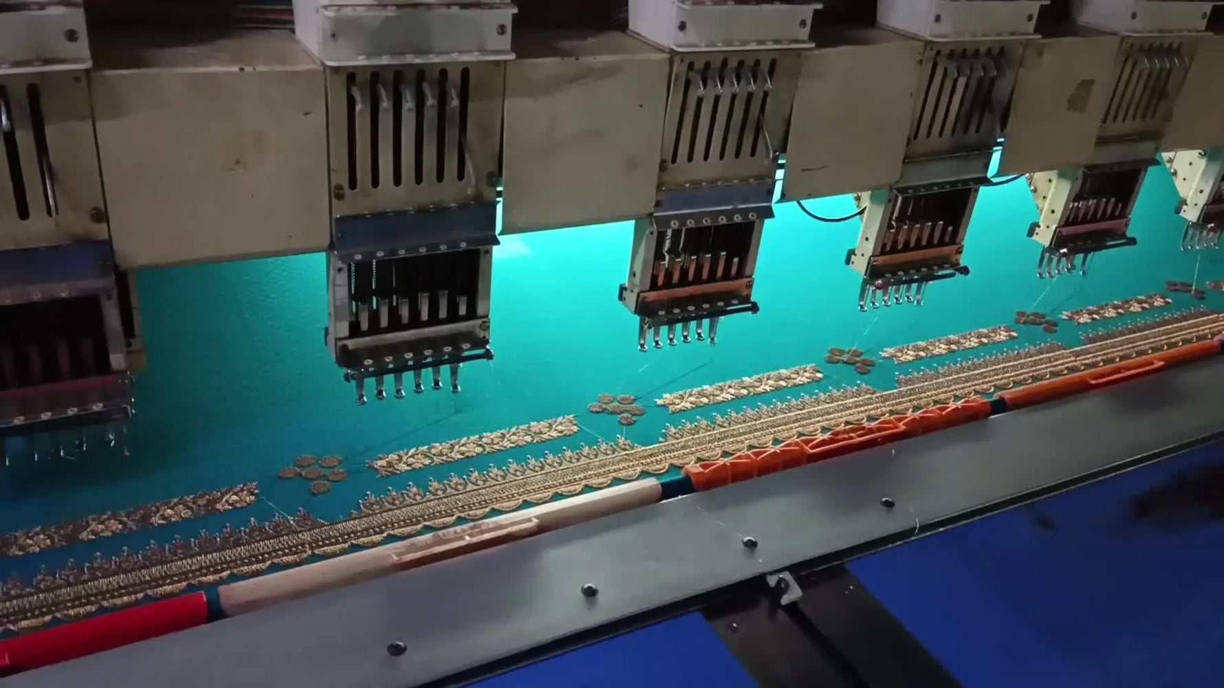 A multi-head industrial embroidery machine on the factory floor, setting the context for a needle-bar locking repair.