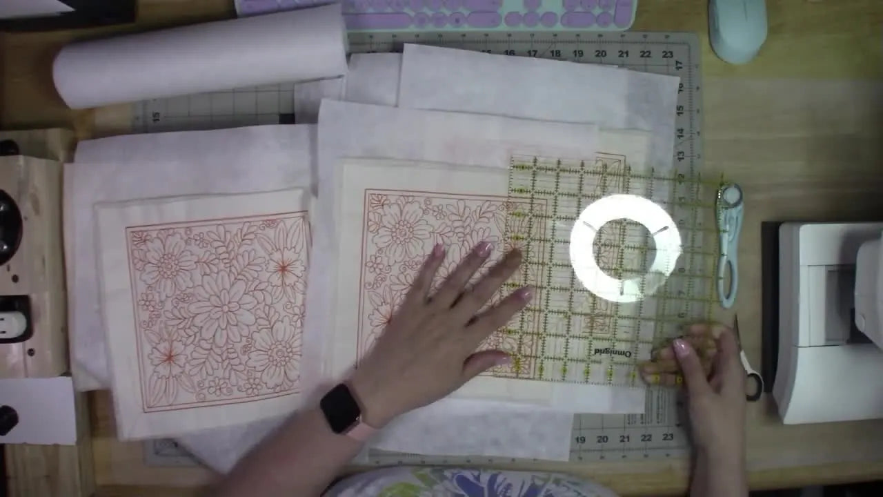 A clear quilting ruler is laid over an embroidered quilt block to confirm the stitched design width at 7.75 inches before any sashing math is done.