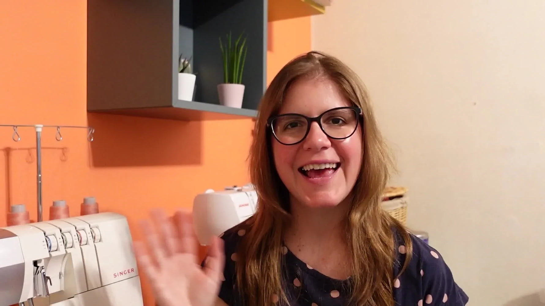 Woman smiling and waving at the camera, introducing the video.