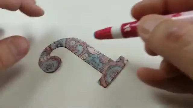 Hands place a pre-cut fabric letter precisely inside the stitched placement outline in the embroidery hoop before tack-down and satin stitching.