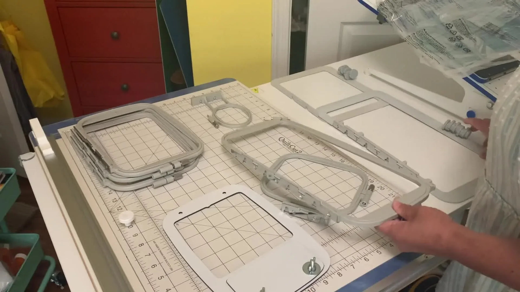 A close view of a flat, white magnetic embroidery hoop being held up and explained as an easier clamping option for a Brother single‑needle machine.