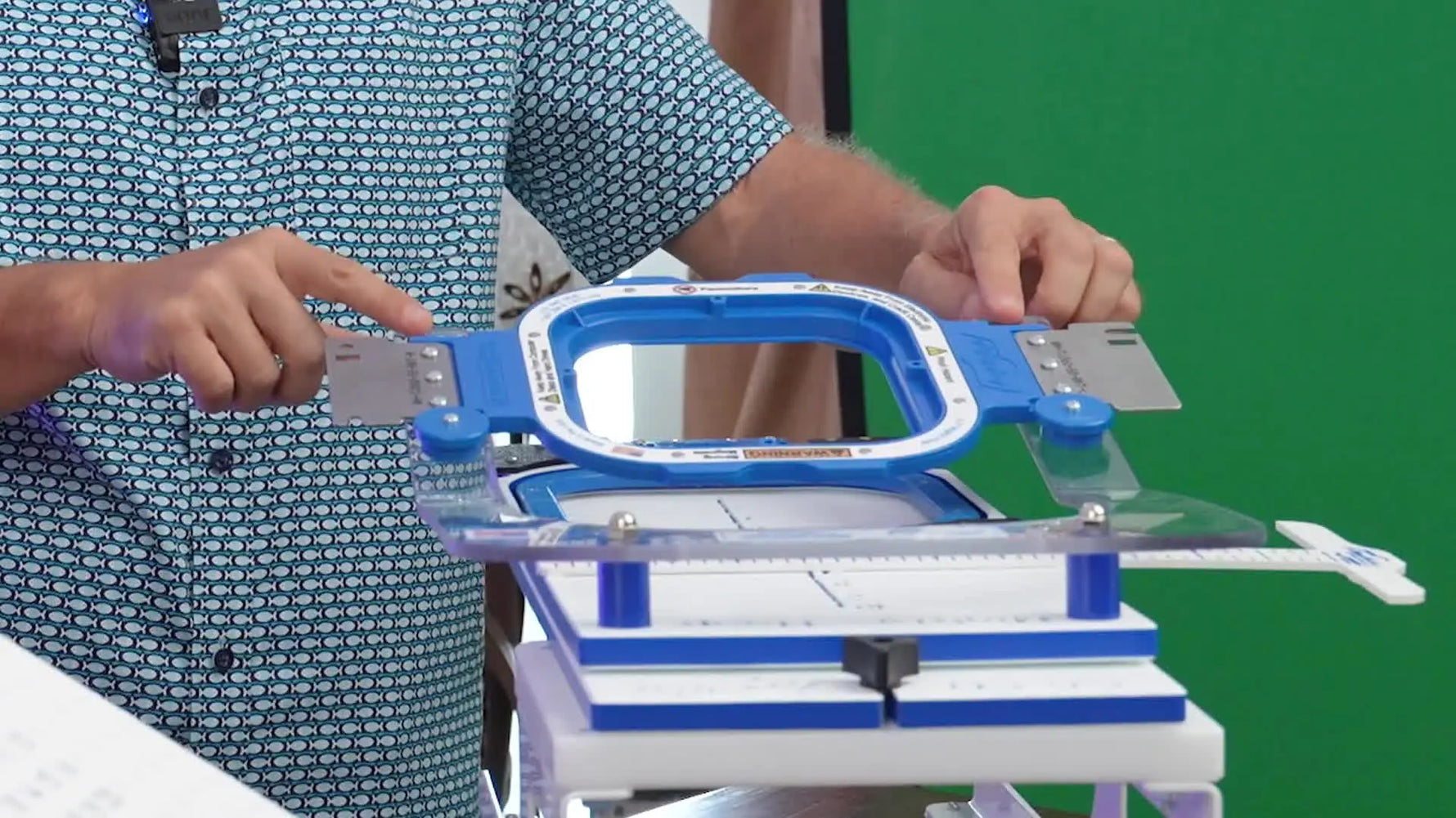 A close action shot of the top magnetic frame snapping down on the Hoop Master station to clamp a garment quickly and squarely.