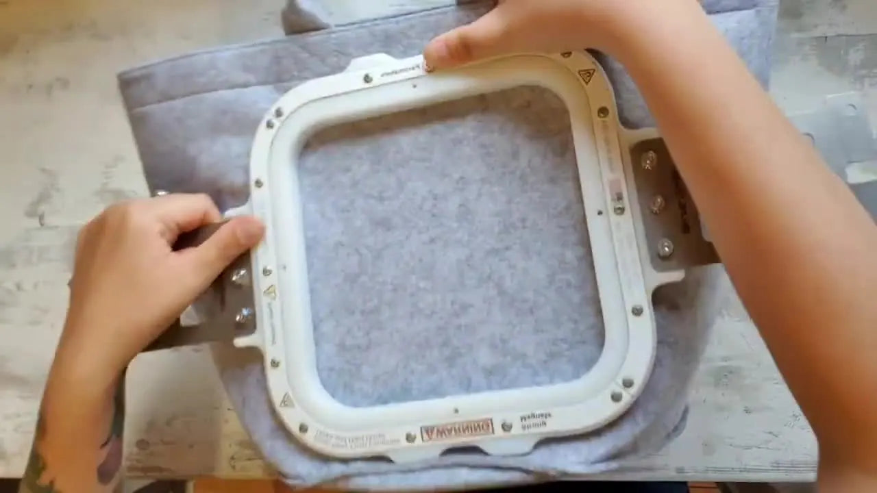 A magnetic hoop clamped cleanly onto a thick felt basket, showing a stable hold without distorting the material.