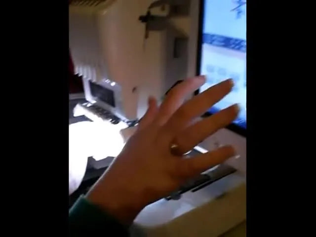 A close-up of the Brother multi-needle machine starting to stitch a name in pink thread onto the plush elephant ear.