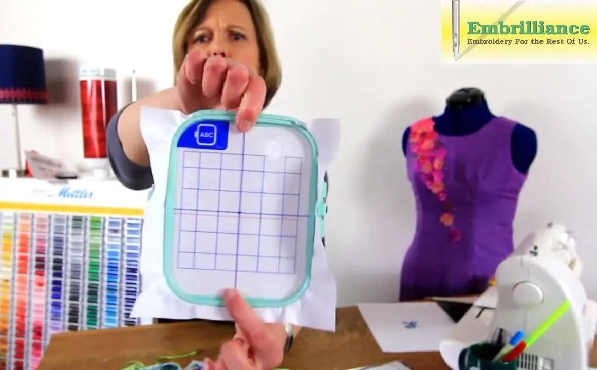 A printed template is compared against a plastic hoop grid, clearly showing the grid’s center line is misaligned from the true machine center.