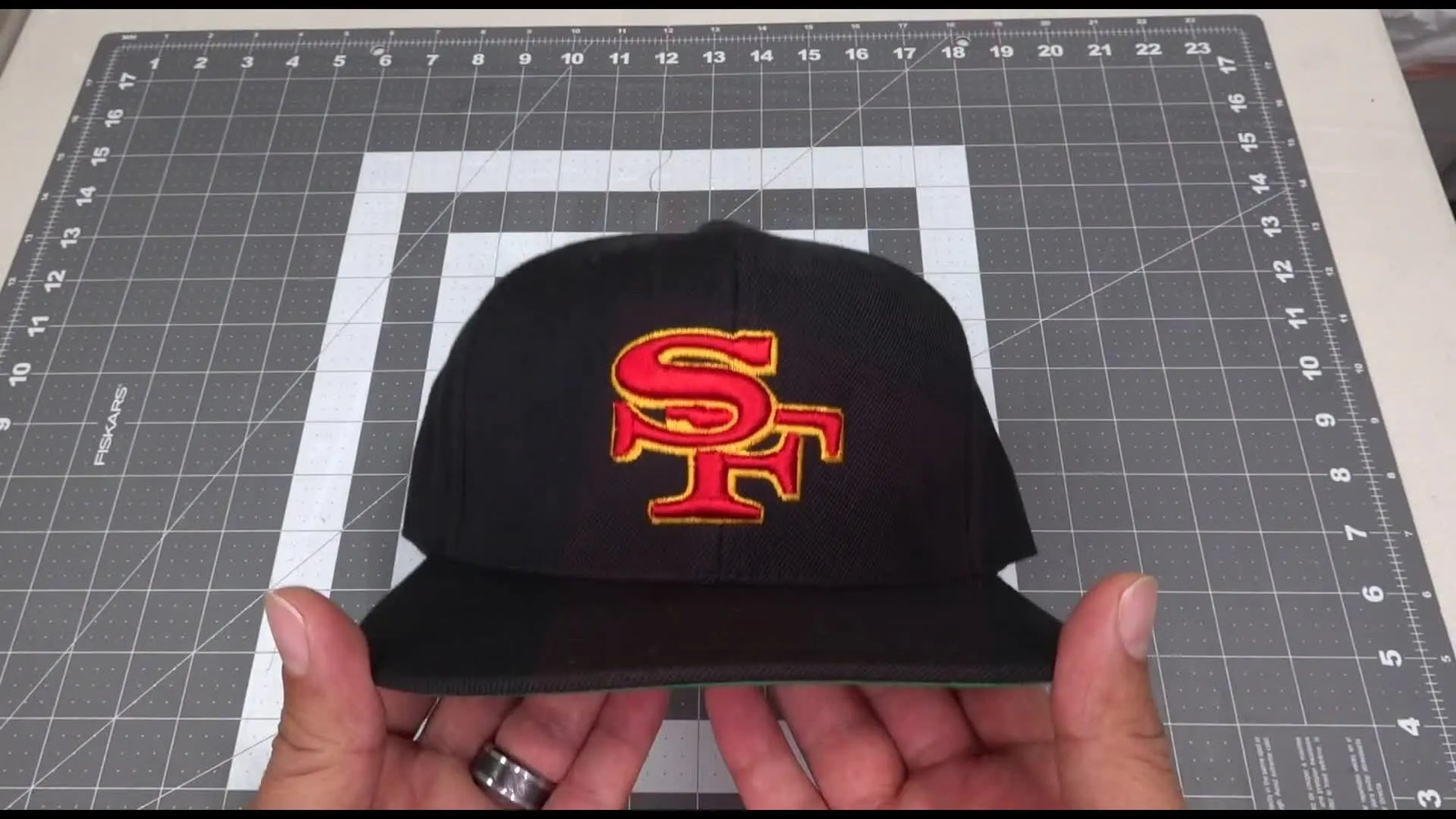 A close-up of the finished raised 3D puff “SF” logo on a black snapback cap with clean edges and strong dimension.