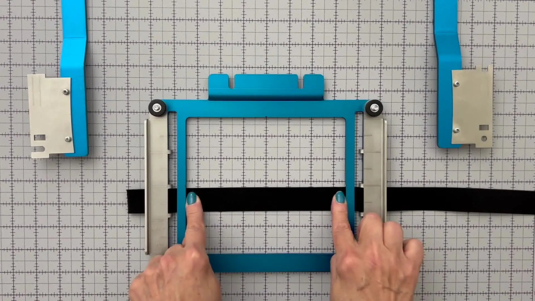 A top-down view of the Durkee EZ Name Frame fully loaded with name tape centered and clamped, ready for fast repeat stitching.