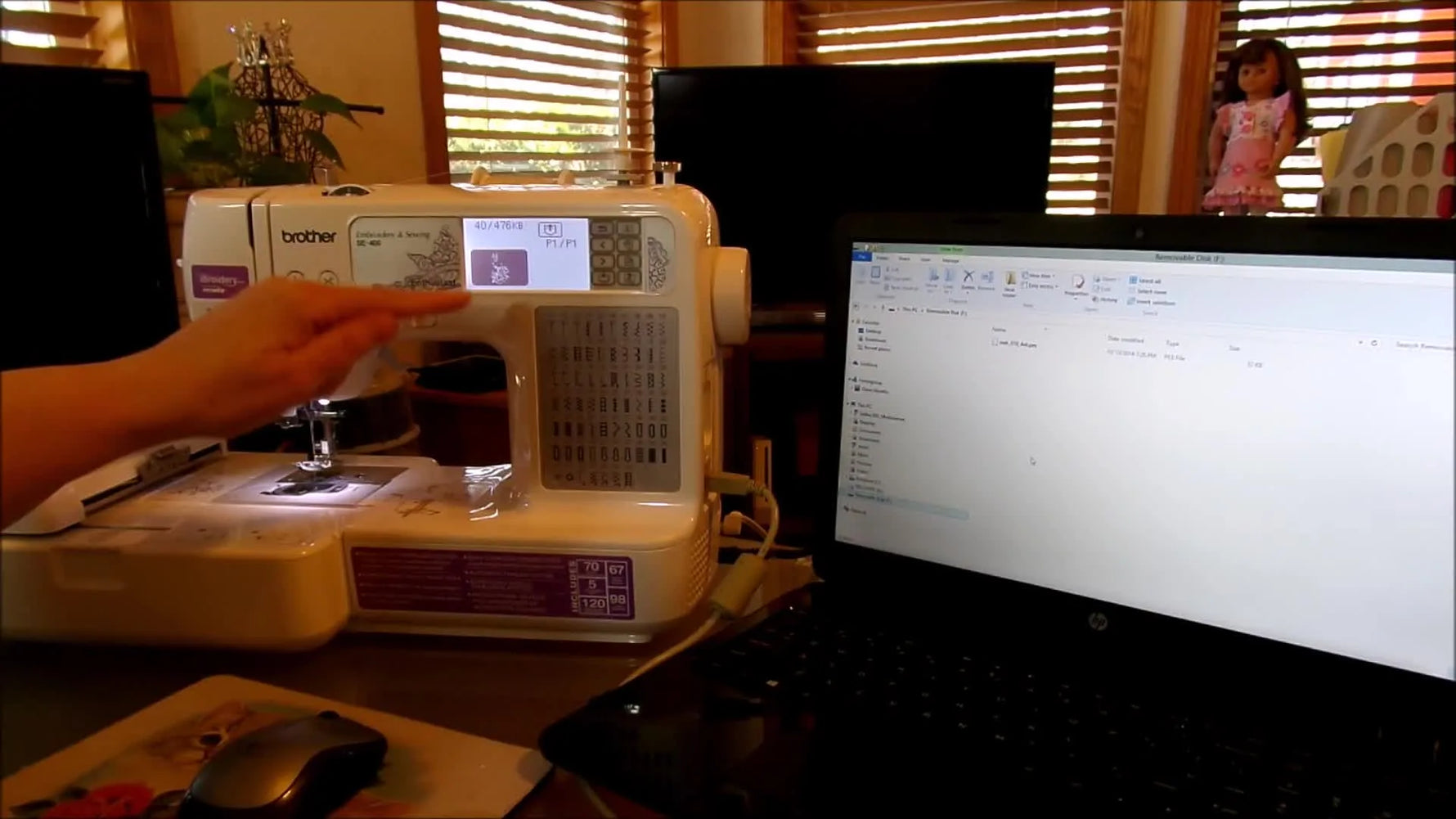 A close-up of the Brother SE400 screen as a finger taps the design icon to invert/highlight it—the critical step that stops the machine from buzzing and refusing the upload.