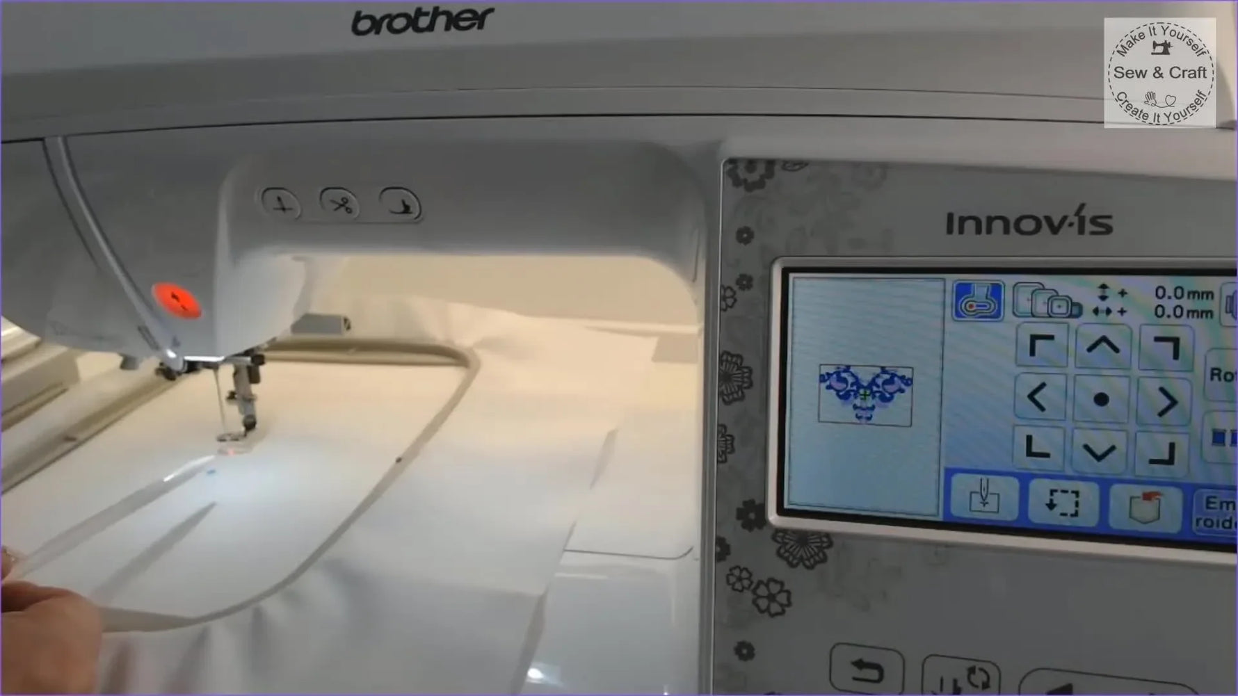 A close-up shows the Brother NV2700 LED pointer’s red dot aligned precisely over a blue fabric mark for accurate embroidery placement.