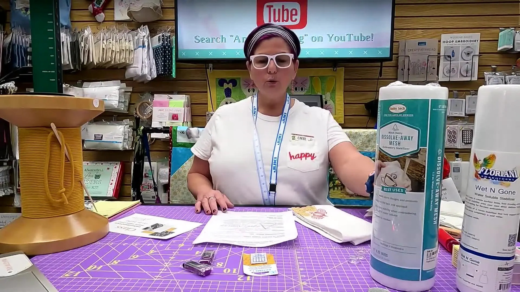 Carol holds up a finished white napkin featuring an autumn-themed free-standing lace corner design.