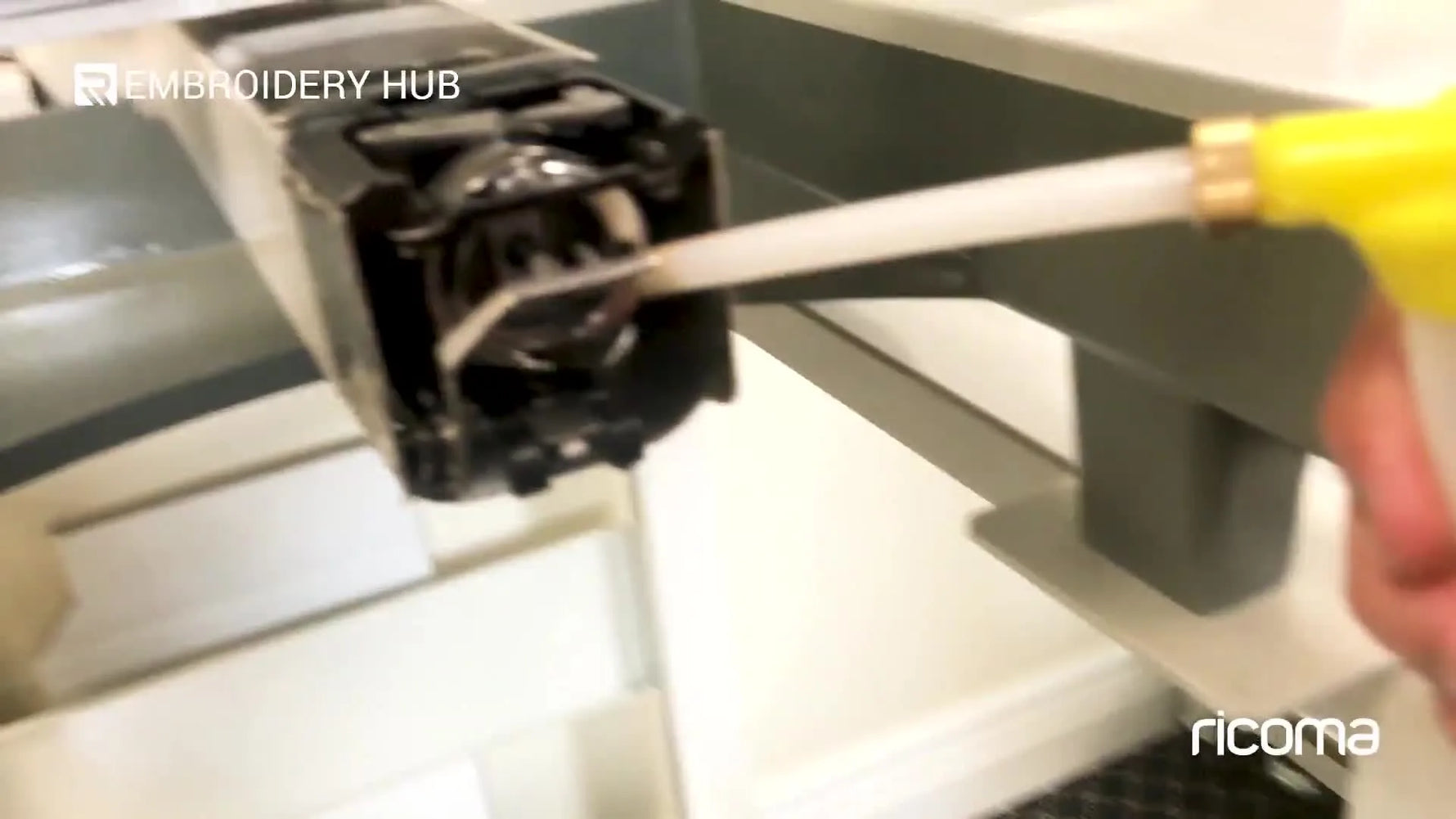 Close-up of sewing machine oil being applied into the rotary hook/bobbin area on a Ricoma TC Series head.