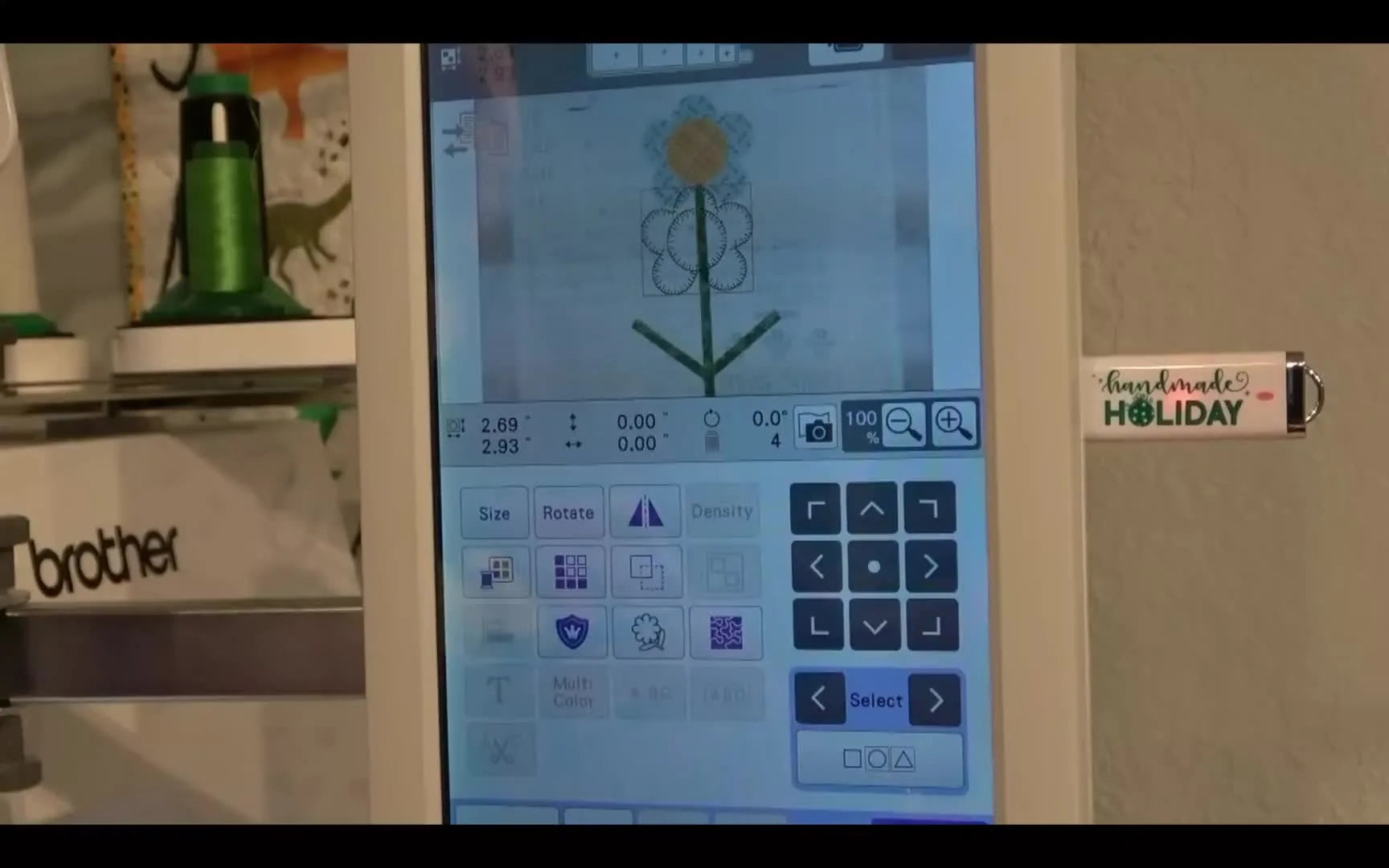 A Brother multi-needle screen shows the live camera background with a digital flower design overlay being nudged into perfect alignment.