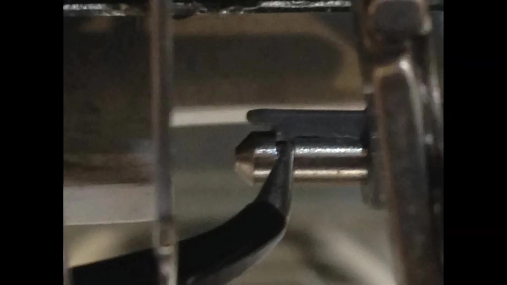 A macro close-up of the Brother needle threader unit showing the locking hook and alignment pins used to remove and install part XC5732151.
