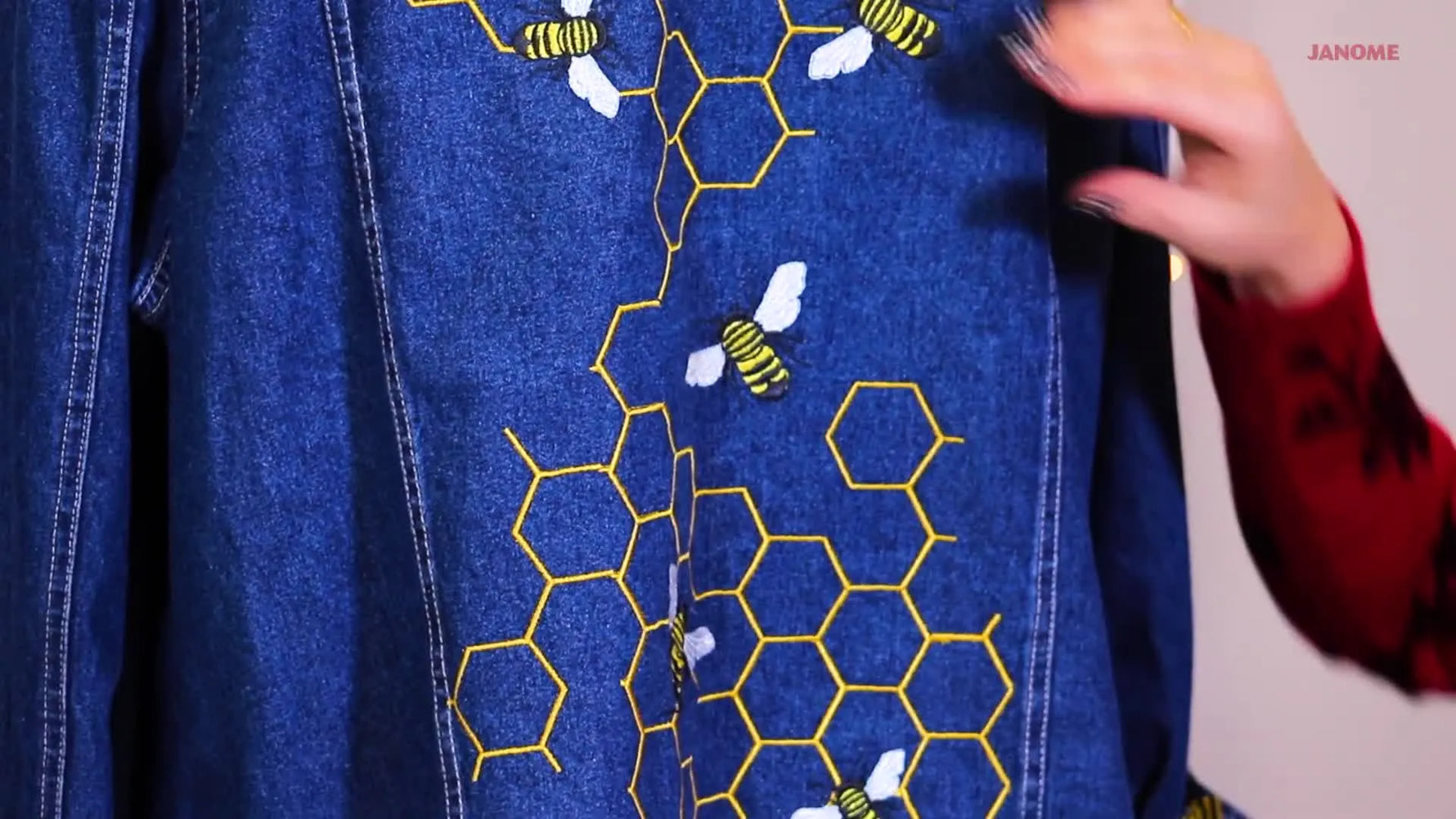 Close-up of the finished honeycomb-and-bee embroidery stitched on denim, showing an organic flow and seam-hiding overlays.