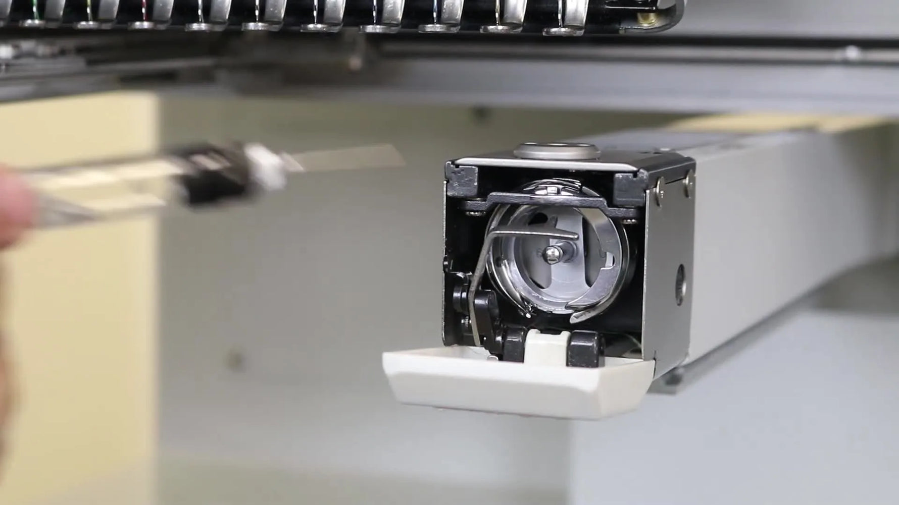 An extreme close-up shows a precision applicator placing oil exactly where the rotary hook track needs it on a Ricoma MT-1502.