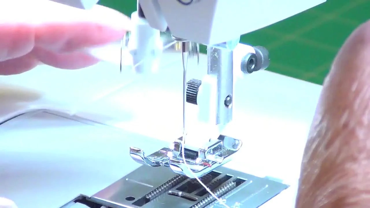 A close-up shows the Designer SE’s automatic needle threader pulling a clean loop through the needle eye.