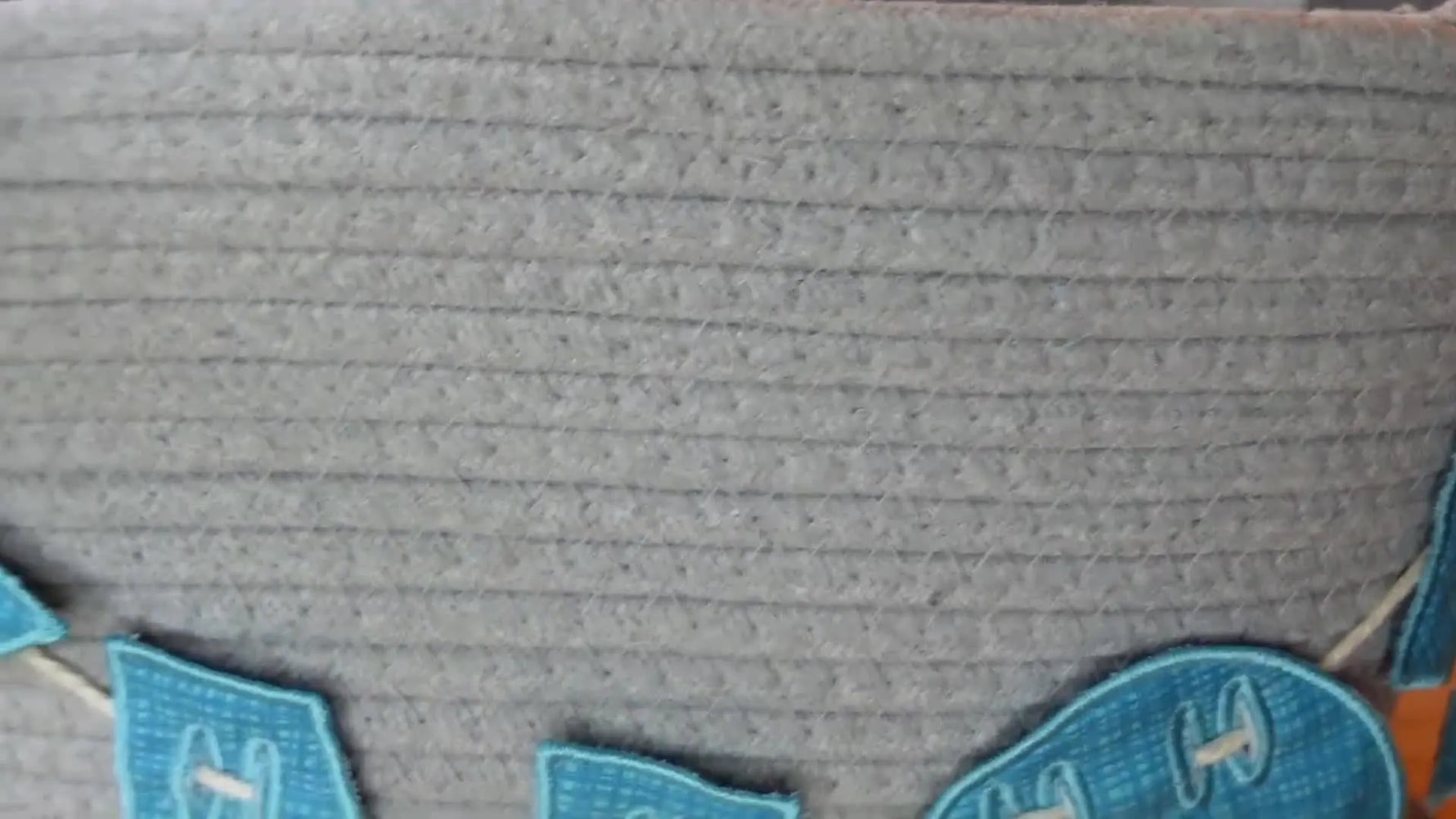 Close-up of the finished 'KNOX' fabric name banner attached to a gray woven basket.