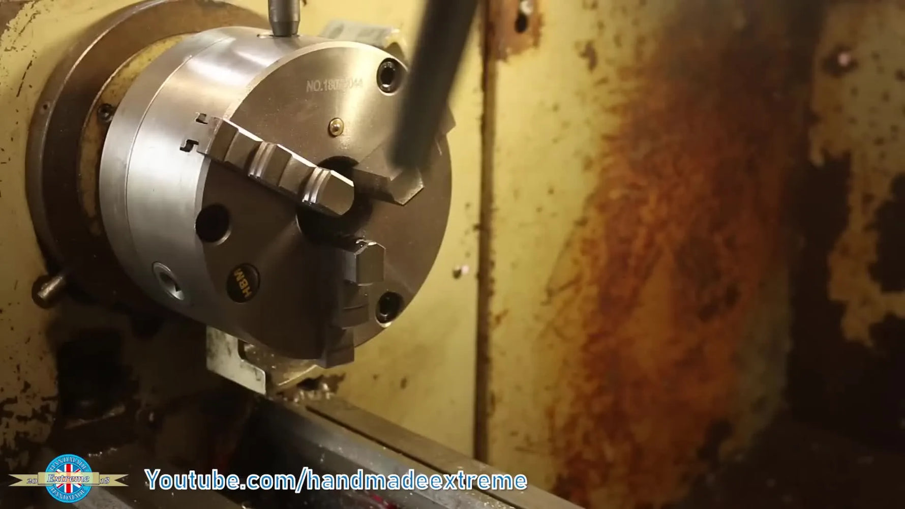 Hand inserting a metal shaft into a lathe chuck