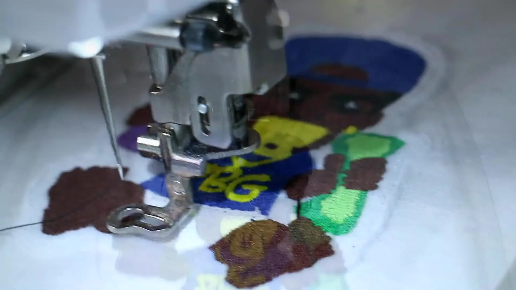 A finished multi-color embroidered patch is held up in a clear sleeve, showing crisp fills and a bold black satin outline.