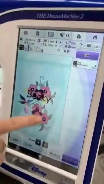 The Brother Dream Machine 2 screen shows a scanned live image of the hooped fabric with the name lettering overlaid for precise placement.