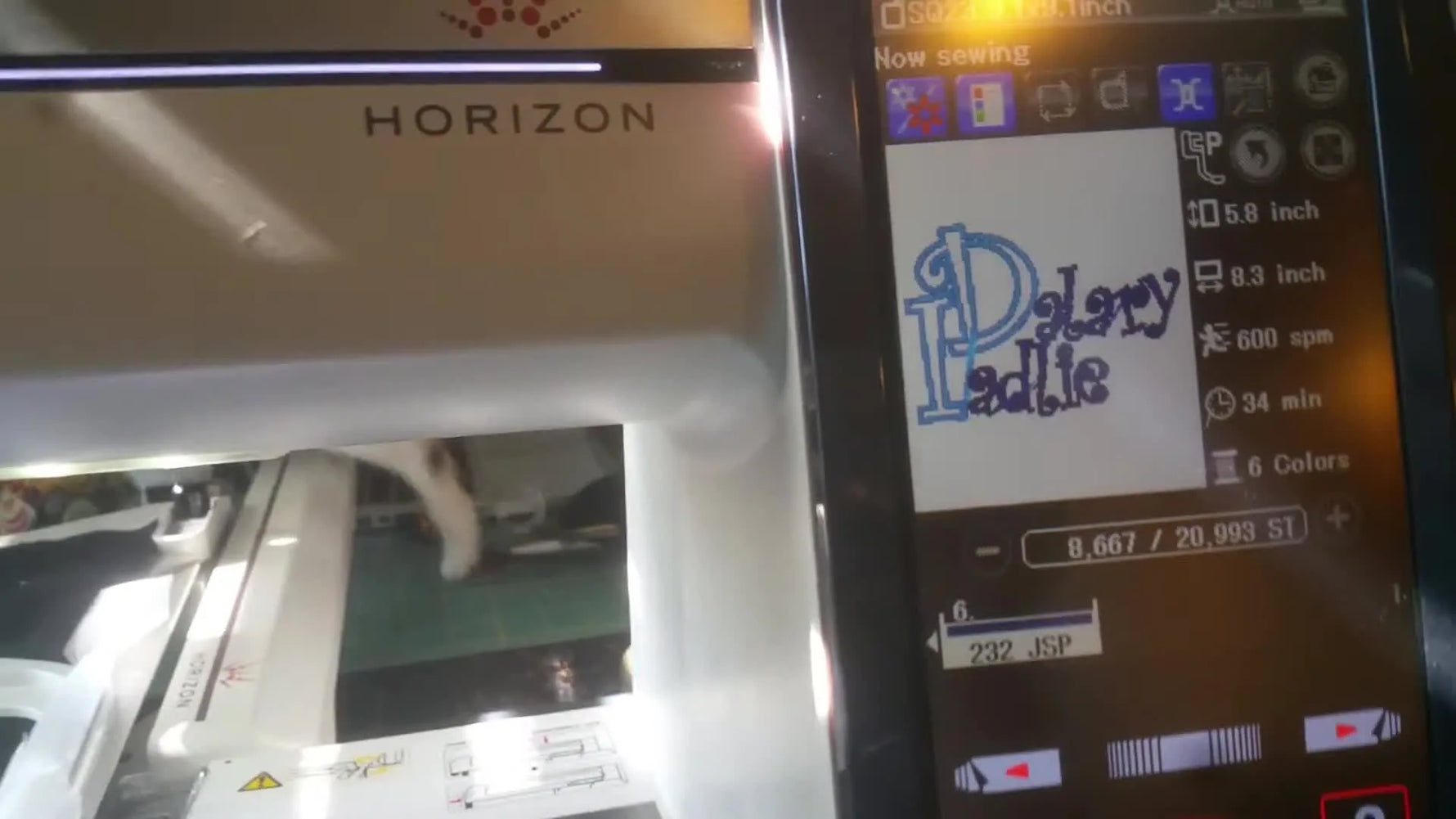 The Janome Horizon MC12000 LCD screen shows the SQ23 hoop selection and live stitch statistics during a large two-line name embroidery.