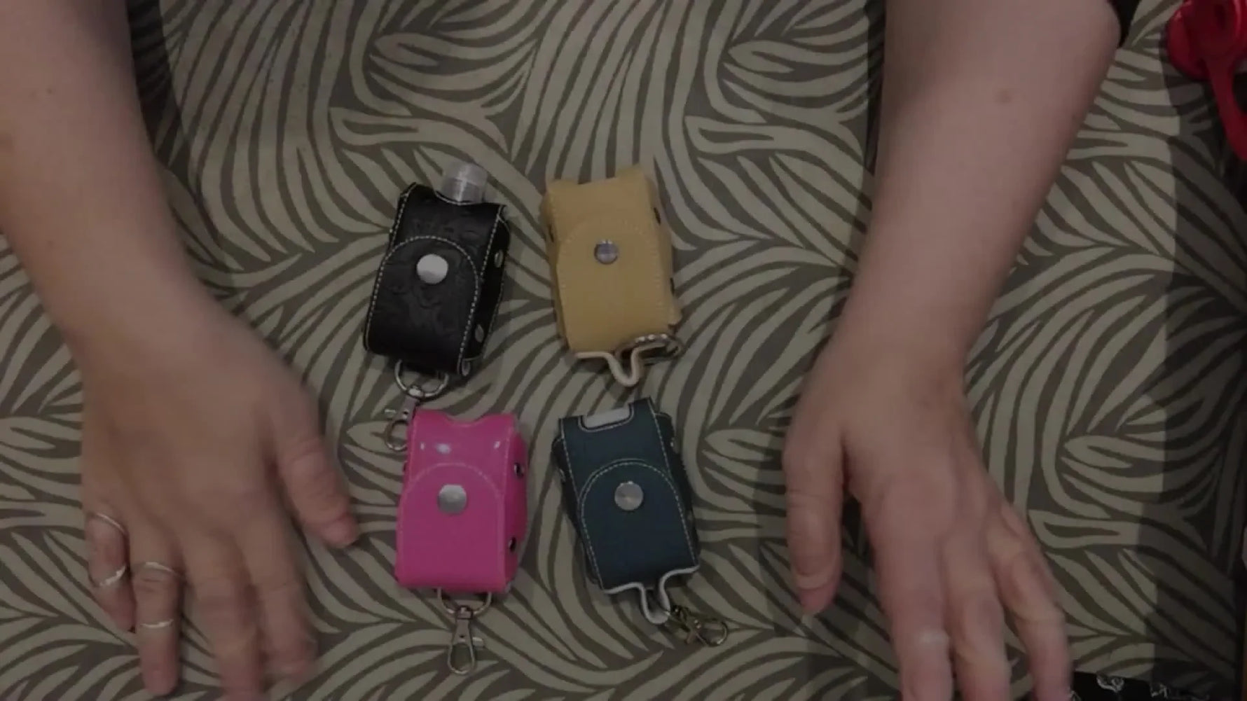 A colorful spread of finished 1 oz ITH sanitizer holders laid out together, showing different vinyl choices and hardware finishes.