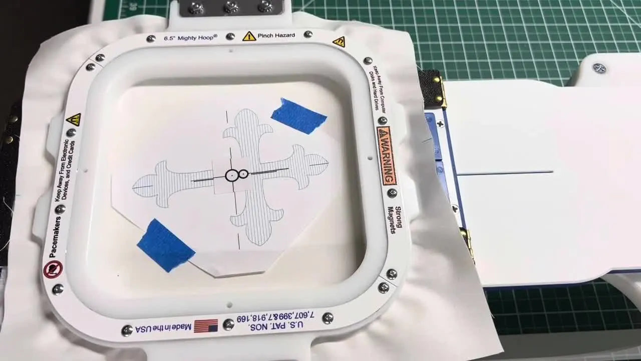 A magnetic Mighty Hoop is fully engaged with fabric hooped slightly crooked, ready for the Snowman alignment scan and a camera clearance check.